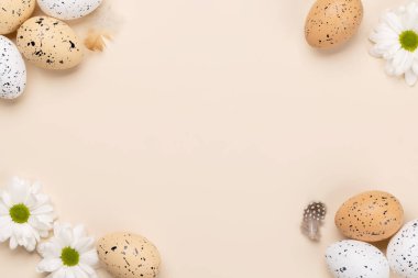 Easter eggs and flowers on a beige background with space for your greetings. Flat lay