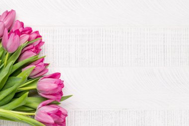 Pink tulip flowers bouquet on white wooden table. Flat lay with copy space