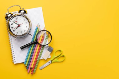 School supplies and stationery on yellow background. Flat lay with blank space