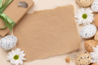 Gift box, Easter eggs and flowers on a beige background with space for your greetings. Flat lay