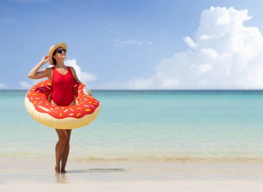 Beautiful young woman with inflatable donut ring relaxing on sea beach. Summer vacation. With copy space