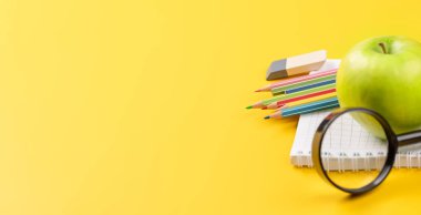 Okul malzemeleri, kırtasiye malzemeleri ve sarı arka planda elma. Eğitim ve beslenme. Boş alanla