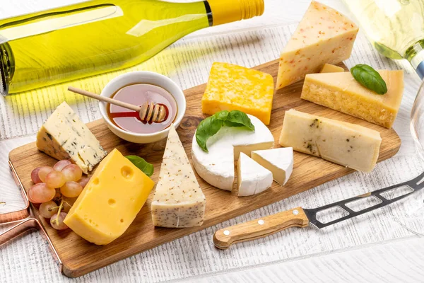 木板上的各种奶酪和白葡萄酒 — 图库照片