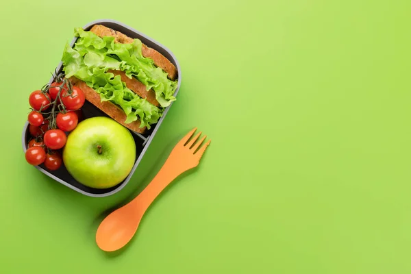 School lunch box on green background. Education and nutrition. Flat lay with blank space