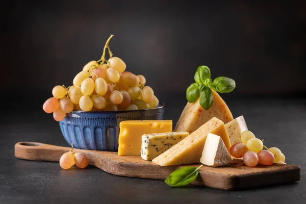 ボード上の様々なチーズとブドウ — ストック写真
