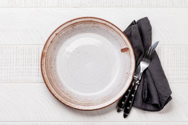Empty plate with fork and knife on white wooden table. Flat lay with copy space