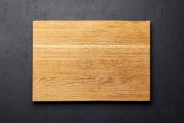 Wooden cutting board on stone kitchen table. Flat lay with copy space