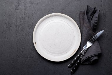 Empty plate with fork and knife on dark stone table. Flat lay with copy space