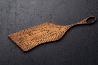 Wooden cutting board on stone kitchen table. Flat lay with copy space