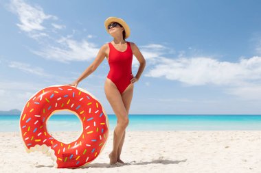 Beautiful young woman with inflatable donut ring relaxing on sea beach. Summer vacation. With copy space