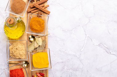 Various dried spices in small bowls on stone table with copy space. Flat lay