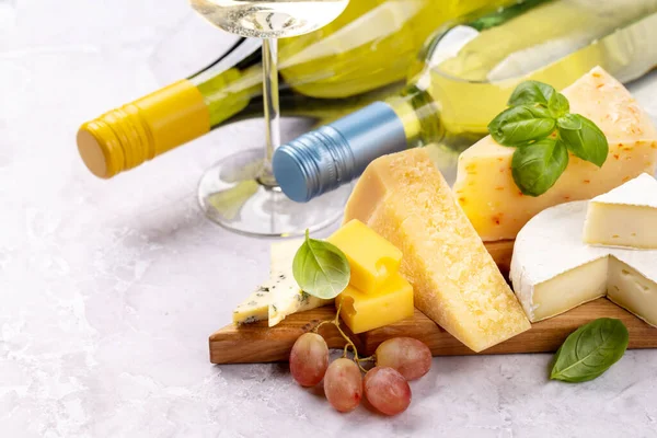 ボード上の様々なチーズと白ワインボトル — ストック写真