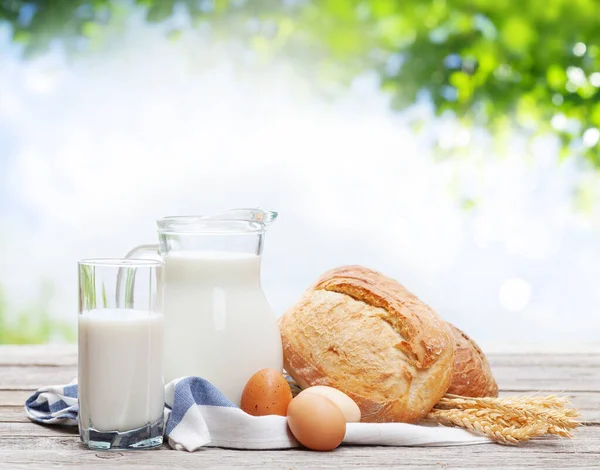 stock image Homemade bread and milk in pitcher on wooden table. Outdoor