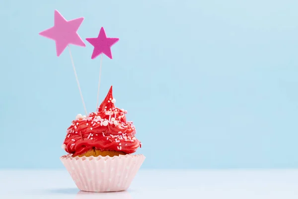 stock image Red cream cupcake with decor on blue background with copy space