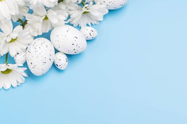 Easter eggs and flower bouquet on a blue background with space for your greetings. Flat lay