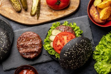 Siyah çörekli ve patates kızartmalı ev yapımı sığır eti burgeri. Düz yatıyordu