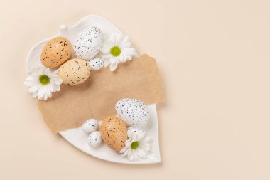 Easter eggs and flowers on a beige background with space for your greetings. Flat lay