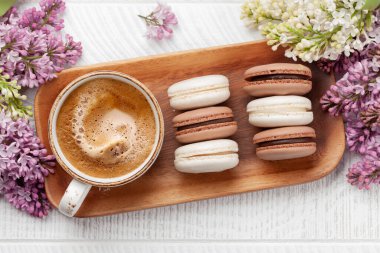 Kurabiye ve kahve. Üzerinde leylak çiçekleri olan ahşap bir masada. Üst görünüm düzlüğü