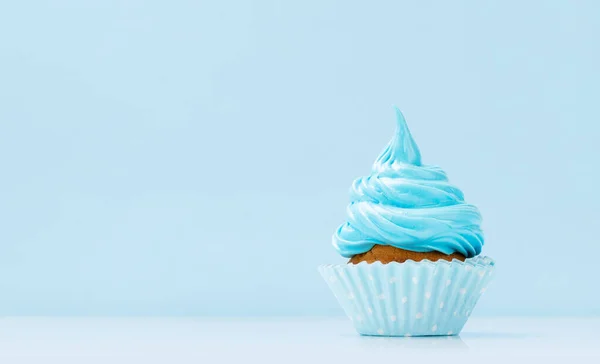 Blue cream cupcake on blue background with copy space