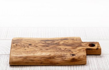 Wooden cutting board on white kitchen table. With copy space