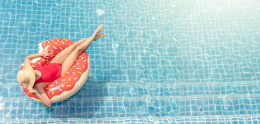 Yüzme havuzunda dinlenen şişme donut yüzüğüyle güzel bir genç kadın. Yaz tatili
