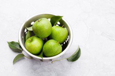 Taş masada kevgire dönmüş taze yeşil elmalar. Kopyalama alanı ile