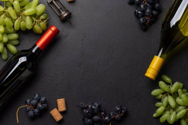 Masada şarap şişesi, üzüm, tirbuşon ve şarap mantarları var.