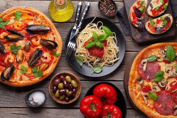 İtalyan mutfağı. Makarna, pizza, zeytin ve kızarmış ekmek. Tahta masanın üzerinde yatıyordu.