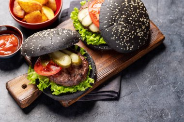 Homemade beef burgers with black buns and french fries