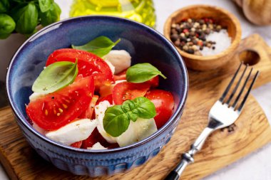 Olgun domatesli Caprese salatası, mozzarella peyniri ve bahçe fesleğeni.