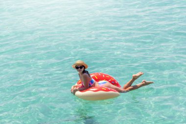 Şişme donut yüzüğüyle denizde dinlenen güzel genç bir kadın. Yaz tatili