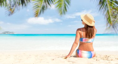 Tropikal deniz sahilinde bikinili bir kadın yazın eğleniyor ve dinleniyor.
