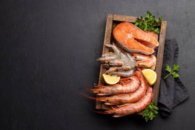 Karides, Langoustines ve ahşap kutuda alabalık bifteği gibi taze deniz ürünleri manzarası. Kopyalama alanı olan düz