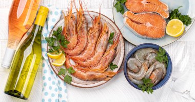 Beyaz ve gül şarabı eşliğinde karides, langoustines ve alabalık bifteği gibi taze deniz ürünlerinin üst görüntüsü