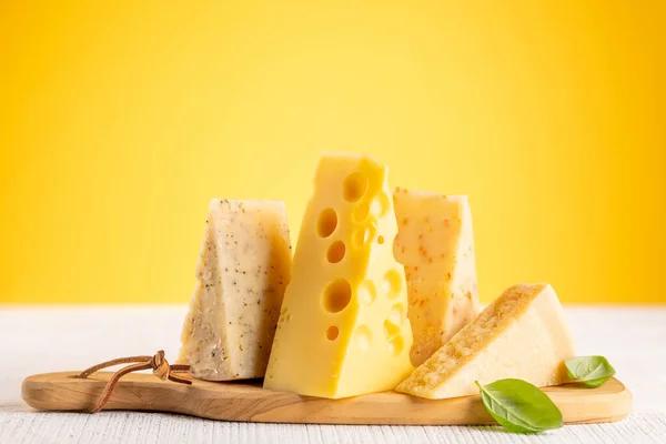 ボード上の様々なチーズ 黄色の背景にコピースペース — ストック写真