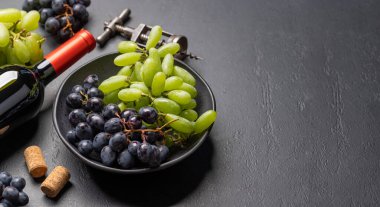 Masada şarap şişesi, üzüm, tirbuşon ve şarap mantarları var.