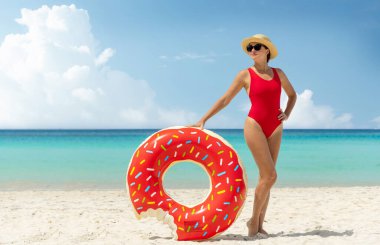 Beautiful young woman with inflatable donut ring relaxing on sea beach. Summer vacation. With copy space