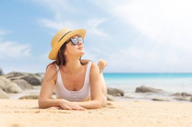 Woman lying on the sea beach enjoying and relaxing in summer