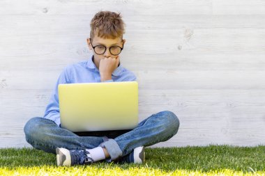 Dışarıda dizüstü bilgisayar kullanan bir çocuk. Eğitim ya da eğlence konsepti