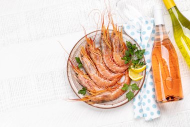 Beyaz ve gül şarabının eşlik ettiği langoustines gibi taze deniz ürünlerinin üst görüntüsü. Kopyalama alanı olan düz