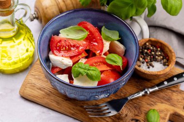 Olgun domatesli Caprese salatası, mozzarella peyniri ve bahçe fesleğeni.