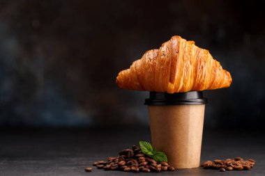 Süslü kruvasanla eşleştirilmiş kağıt bardaktaki Aromatik kahve. Kopyalama alanı ile