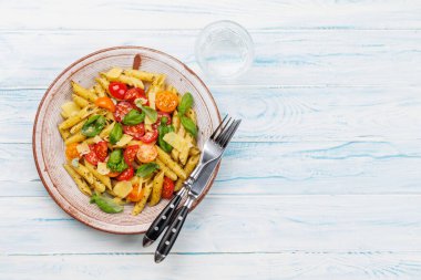 Taze domates ve aromatik fesleğen yapraklarıyla süslenmiş nefis bir tabak İtalyan makarnası. Kopyalama alanı olan düz