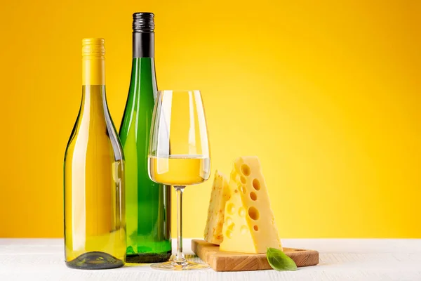 ボード上の様々なチーズと白ワイン 黄色の背景にコピースペース — ストック写真