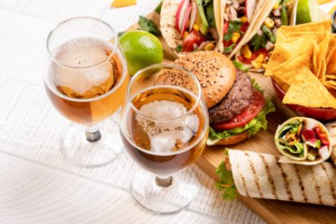 Tako, burrito, nacho, hamburger ve bira içeren Meksika yemekleri.