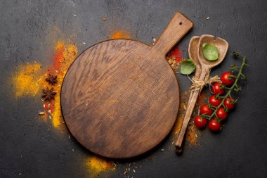 Empty cutting board over various spices on stone table. Frame with copy space for your menu or recipe