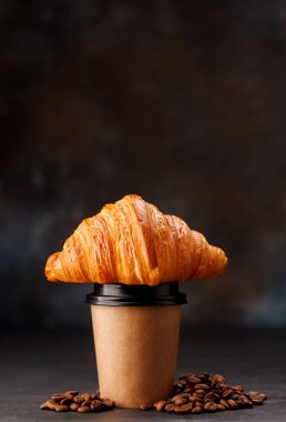 Süslü kruvasanla eşleştirilmiş kağıt bardaktaki Aromatik kahve. Kopyalama alanı ile