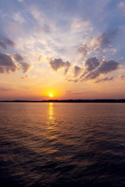 Doğanın güzelliğini ve o anın huzurunu gözler önüne seren, nehrin üzerinde çarpıcı bir günbatımı manzarası.