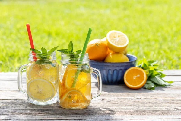 新鲜的自制柠檬水放在室外花园的桌子上 夏天的冷饮 带有新鲜柑橘类水果和花园薄荷 — 图库照片