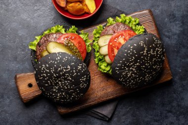 Siyah çörekli ve patates kızartmalı ev yapımı sığır eti burgeri. Düz yatıyordu